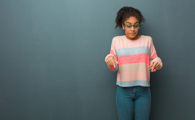 Fototapeta premium Young african american girl with blue eyes pointing down