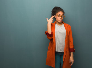 Young black african american girl with blue eyes doing a suicide gesture