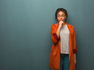Young black african american girl with blue eyes doubting and confused