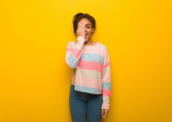 Young black african american girl with blue eyes shouting happy and covering face with hand