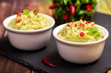 The traditional dish of Mexican cuisine. Guacamole. Avocado sauce with lime and chili. In a white...