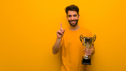 Young man holding a trophy showing number one