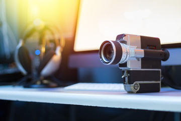 Movie production: vintage old movie camera on a desk, cutting room in the background. Sunshine.