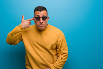 Young colombian man doing a disappointment gesture with finger