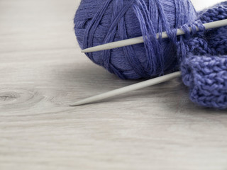 All for needlework: a ball of lilac thread, knitting, knitting needles on a wooden gray table. View...