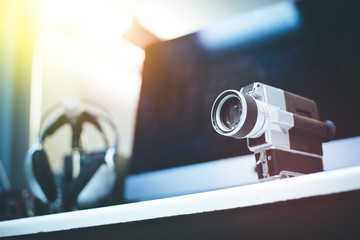 Movie production: vintage old movie camera on a desk, cutting room in the background. Sunshine.