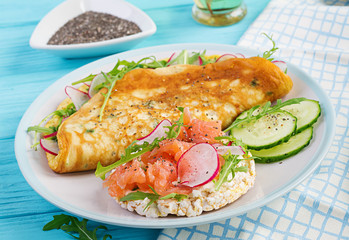Breakfast. Omelette with radish, green arugula and sandwich with salmon on white plate.  Frittata - italian omelet.