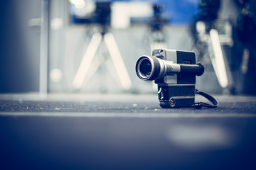 Movie production: vintage old movie camera on a desk, production studio in the background