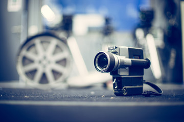 Movie production: vintage old movie camera on a desk, production studio in the background