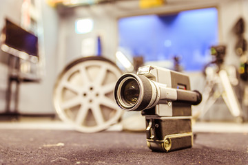 Fototapeta premium Movie production: vintage old movie camera on a desk, production studio in the background