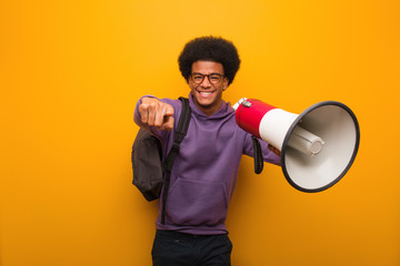 Young african american man holdinga a megaphone cheerful and smiling pointing to front