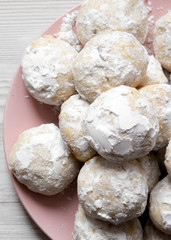 Homemade white mexican wedding cookies on pink plate over white wooden surface, top view. Flat lay, overhead, from above.
