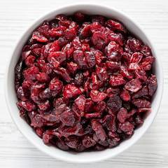 Top view, dried cranberries in a bowl over white wooden background. From above, overhead, flat lay. Close-up.