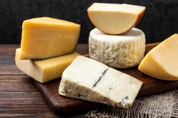 Fototapeta na wymiar Cheese on dark wooden background.