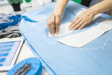 Sewing workshop. Seamstress at work. Marking and cutting fabric.