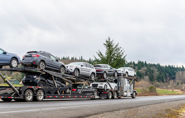 Big rig car hauler semi truck transporting cars on special two level modular semi trailer