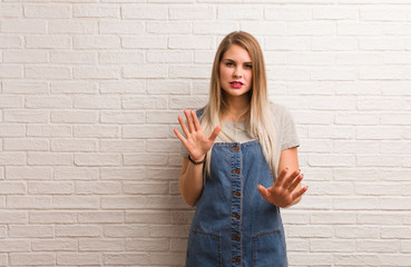 Young russian hipster woman rejecting something doing a gesture of disgust