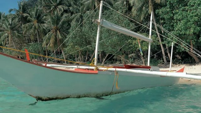Close-up shot of traditional filipino bangka boat anchored on gorgeous tropical beach. Travel concept. Palawan island, Philippines.