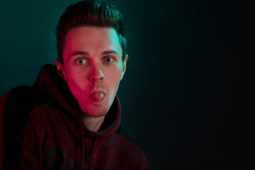 Studio portrait of a grimacing guy in a hoodie.