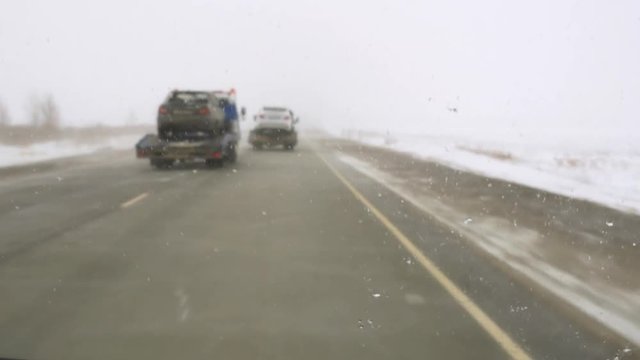 dangerous route in ice and blizzard, two tow trucks transporting cars