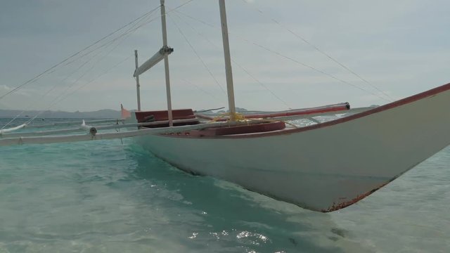 Close-up shot of traditional filipino bangka boat anchored on gorgeous tropical beach. Travel concept. Palawan island, Philippines.