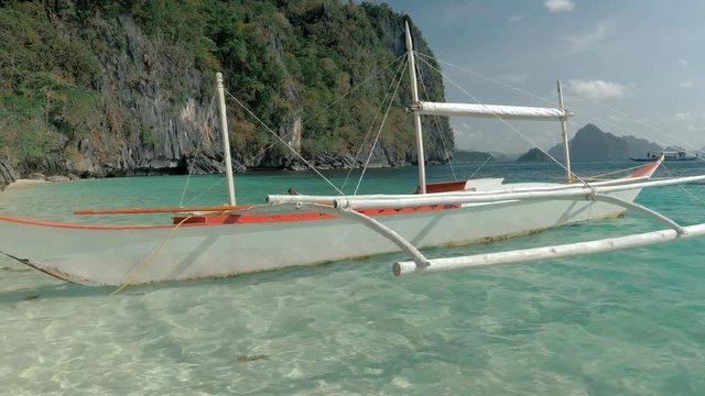 Close-up shot of traditional filipino bangka boat anchored on gorgeous tropical beach. Travel concept. Palawan island, Philippines.