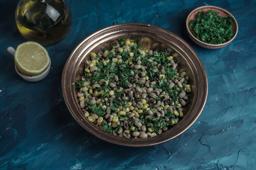Appetizers dry cowpea salad with corns and parsley on blue background