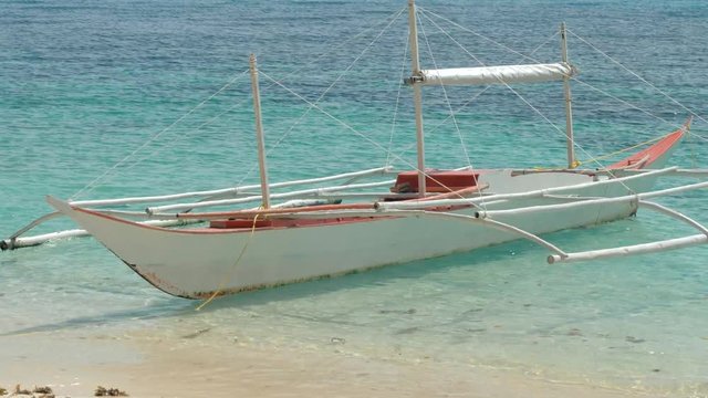 Close-up shot of traditional filipino bangka boat anchored on gorgeous tropical beach. Travel concept. Palawan island, Philippines.