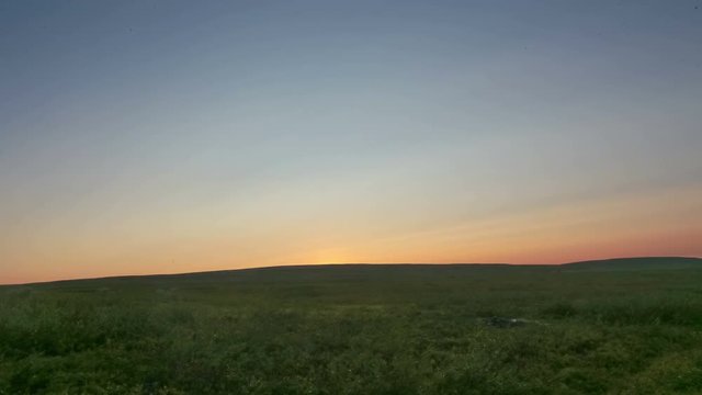 Midnight sun on the horizon and rising with few rolling clouds