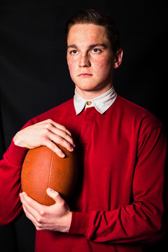 Redheaded man in red shirt holding ball for ragby