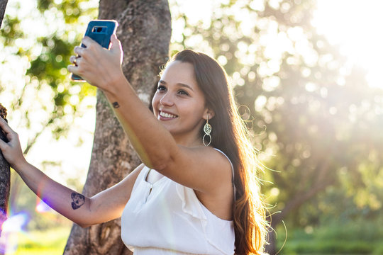 young girl taking selfie photos with her mobile phone in the park 