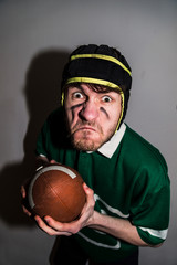 Rugby player with ball looking angry at camera