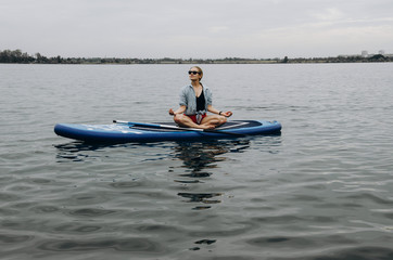 Fototapeta na wymiar Woman on sup board. A beautiful young woman relaxes on a SUP board. Standup paddleboarding