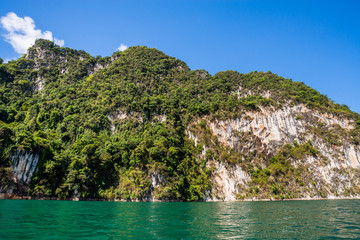 Naklejka na ściany i meble Beautiful nature rock mountains cliff and blue emerald water color lake river with blue clear sky in Ratchaprapa Dam at Khao Sok National Park, Surat Thani Province, Thailand. Asia tourism location.