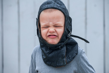 Slavic children from orphanage in old clothes gathered by parishioners of church play behind tall wooden fence with plastic auto painted in gray paint. Boys dreams about freedom, forest, river, plane