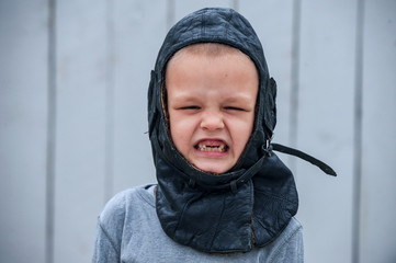 Slavic children from orphanage in old clothes gathered by parishioners of church play behind tall wooden fence with plastic auto painted in gray paint. Boys dreams about freedom, forest, river, plane