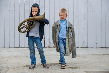 Slavic children from orphanage in old clothes gathered by parishioners of church play behind tall wooden fence with plastic auto painted in gray paint. Boys dreams about freedom, forest, river, plane