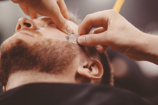 Closeup of razor blade cutting man beard Barbershop