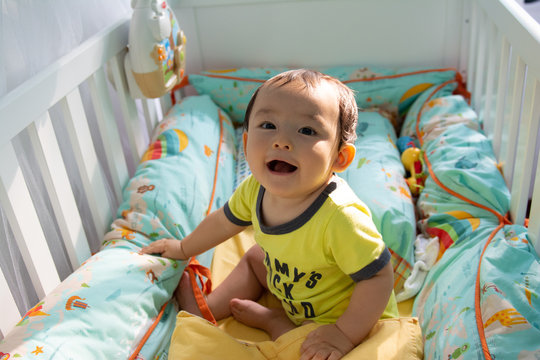 Baby boy playing in the crib funny happy smile 