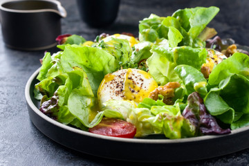 Traditioneller deutscher Sommer Salat mit Blattsalat, Ziegenkäse und Mango Dressing als closeup auf einem Modern Design Teller