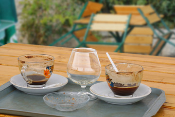 Empty cups from coffee and cognac on a wooden table. End of the holiday season.