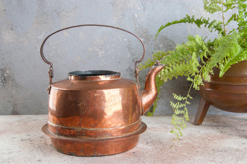 Antique copper kettle on concrete background.