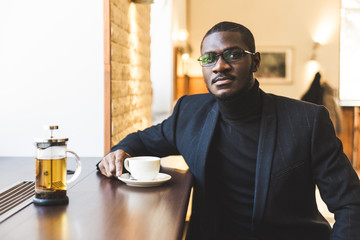 Young handsome dark-skinned businessman in a cafe with a cup of tea.