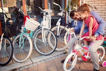 father and daughter having fun outdoor buying new bicycle in store.