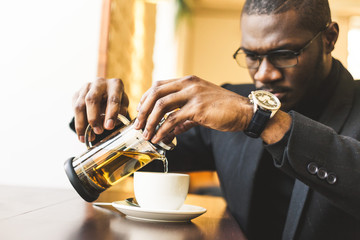 Young handsome dark-skinned businessman in a cafe with a cup of tea.