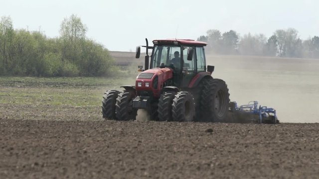 Slow motion shot of Farming tractor moving on agricultural field for plowing land. Agricultural tractor plowing field