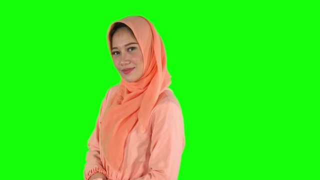 Beautiful female muslim model posing in the studio while wearing islamic clothes and smiling at the camera. Shot in 4k resolution with green screen background