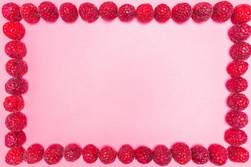 Frame made from fresh raspberries, top view, flat lay, isolated on a light pink background with copy space in the middle.