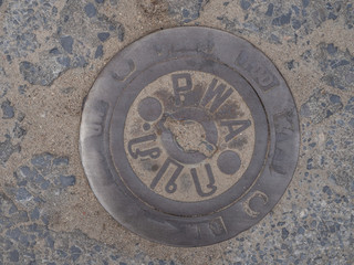 Manhole cover on pavement with patterns. Thailand.