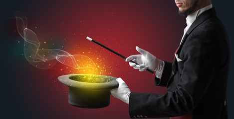 Illusionist hand starts to conjure with white glove and magic wand